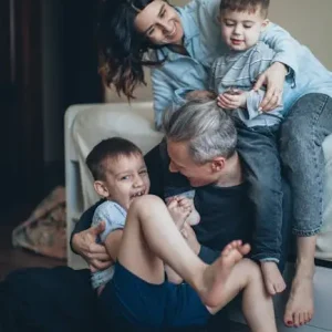 Joyful family of four playing affectionately together indoors, sharing a bonding moment.